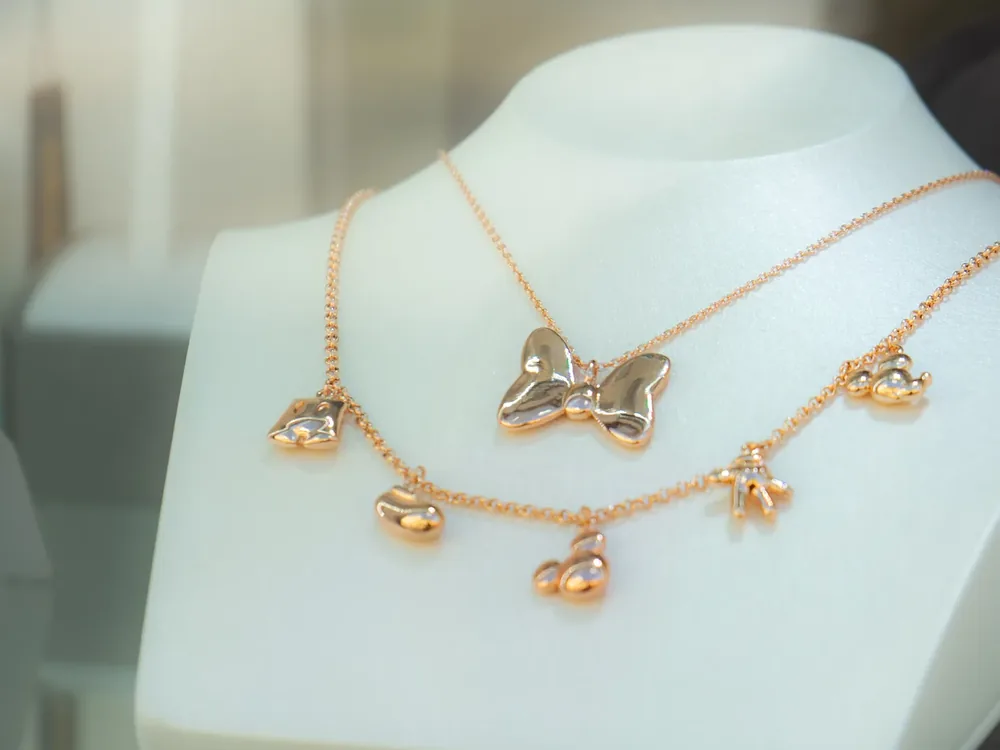 Couture Kingdom rozé arany színű nyaklánc masnis és szív alakú függőkkel, kirakati nyakbábun